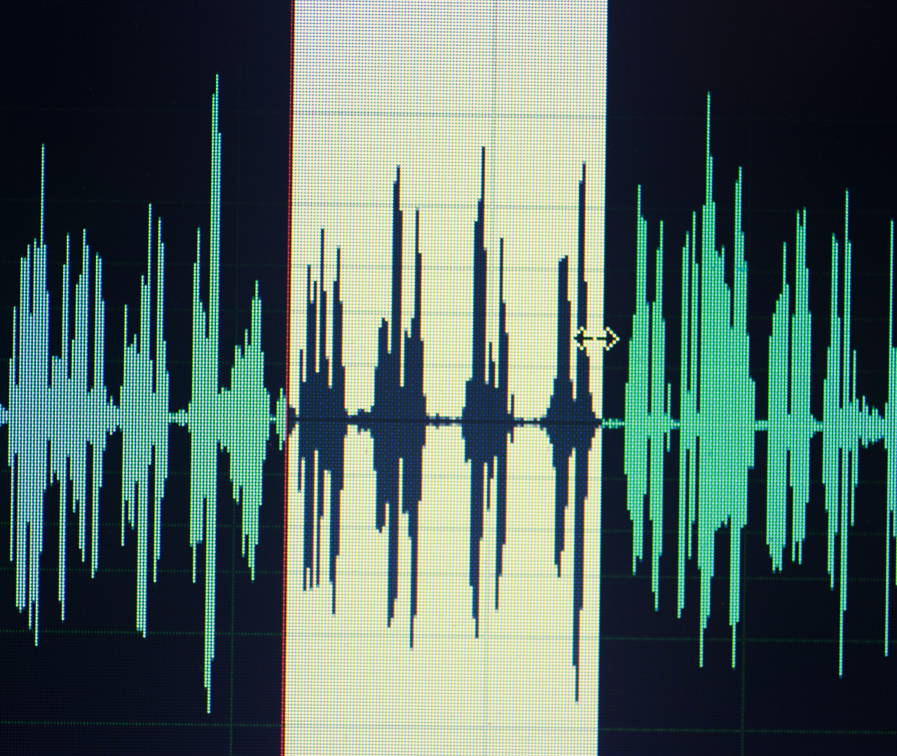 Close-up of a digital audio waveform on a computer screen, showing sound amplitude variations and a selected segment highlighted in yellow.